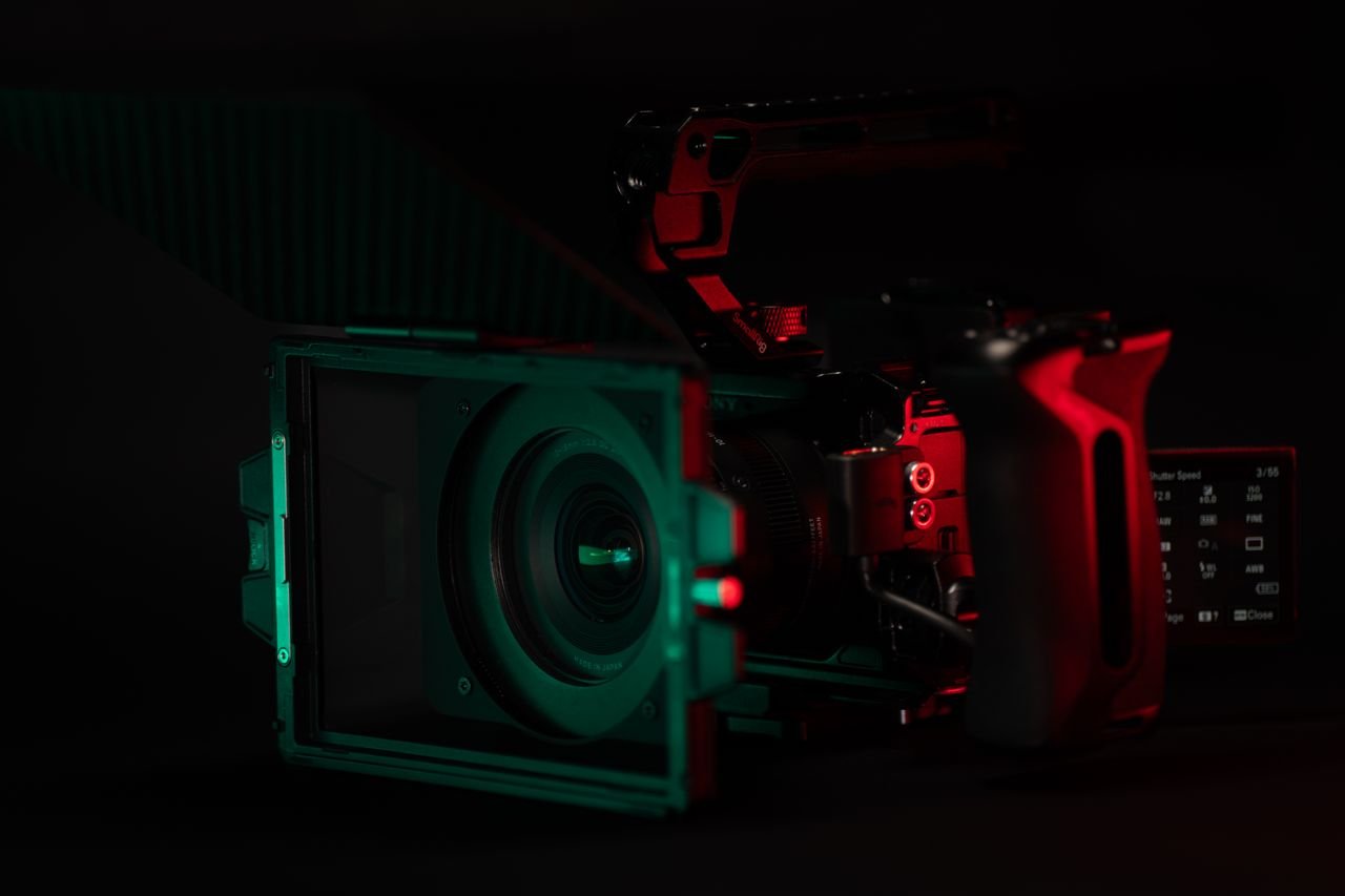 Close-up of a cinema camera rig with striking neon lighting, perfect for videography setups.